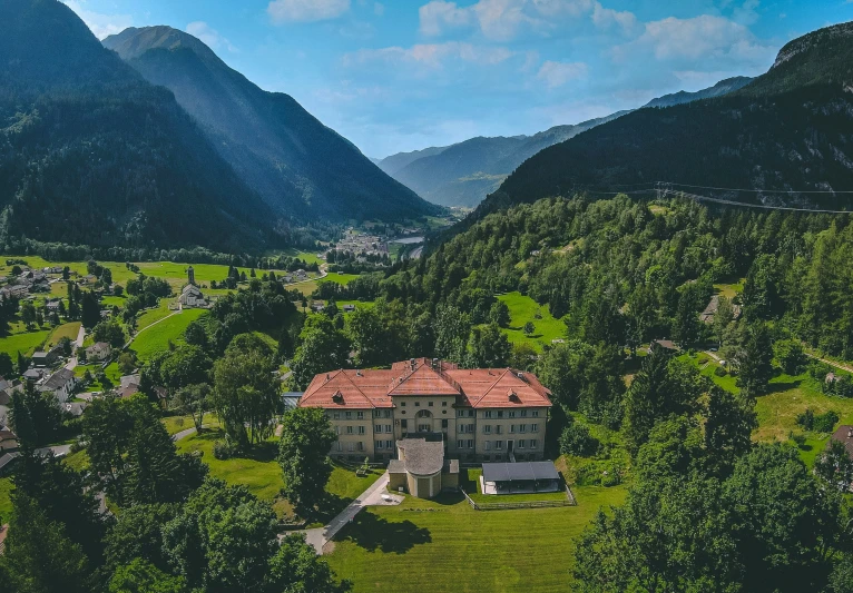 a big mansion with a red roof nestled near mountains