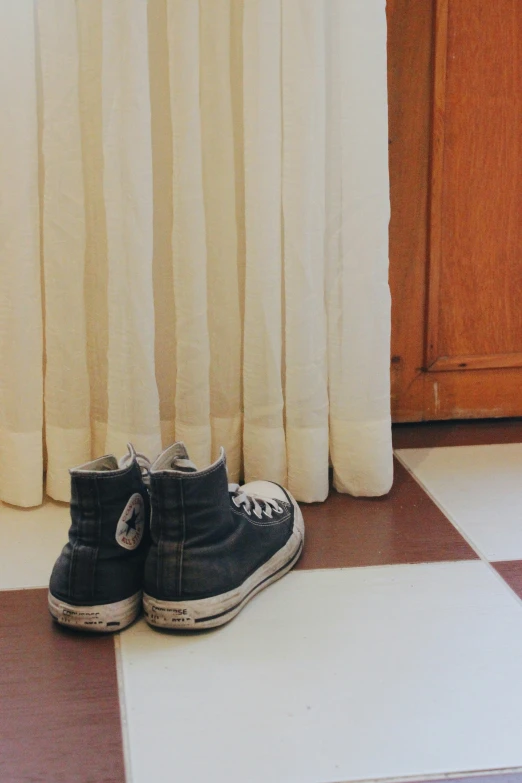 the black and white sneakers are next to the curtains