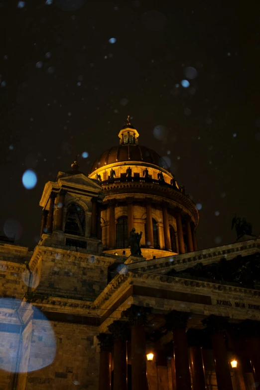 building with lights on at night with snow falling