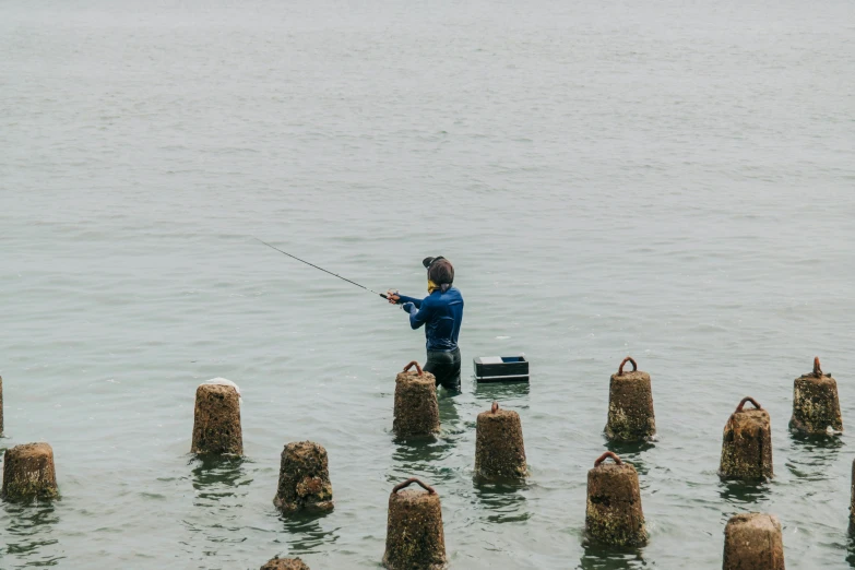 a young man fishing in the sea with poles