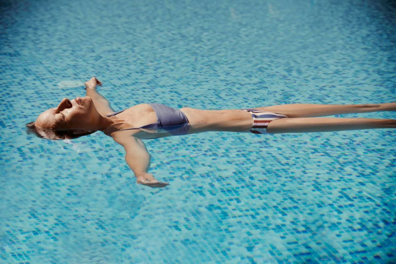 a woman floating in the middle of a pool wearing a swimsuit