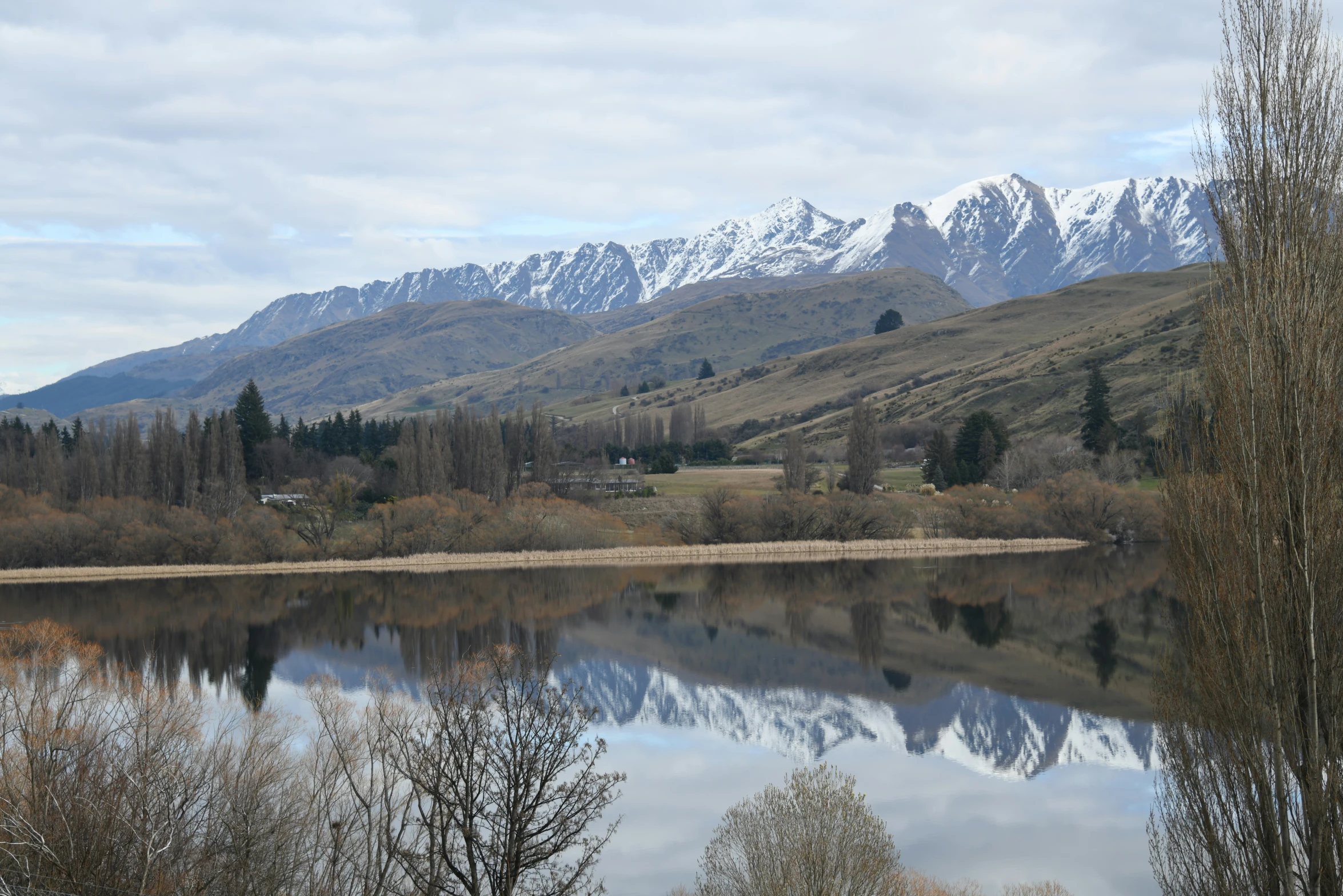 mountains reflected in water near woods and grasses