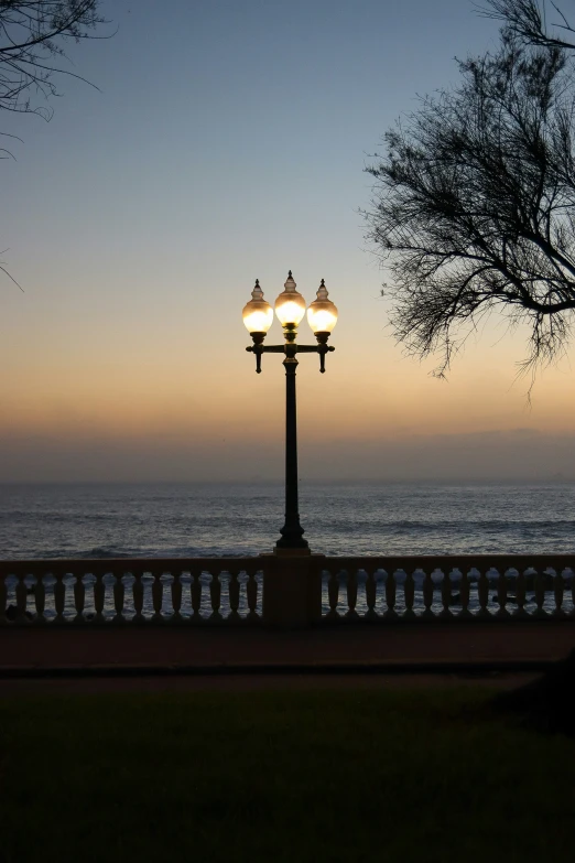 two lights sitting on top of a light pole next to the ocean