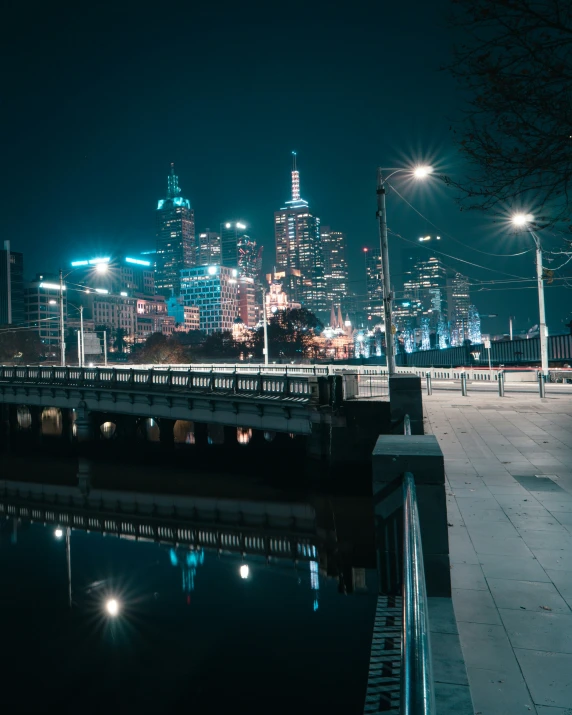 view of city skyline at night with water and bridge