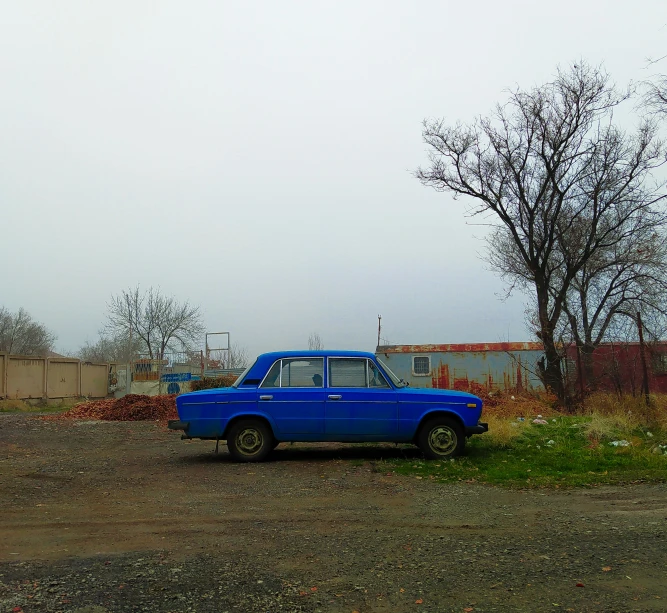 an old, blue truck is parked on the side of the road