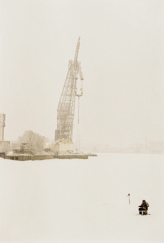 a large crane on top of a white building next to a body of water