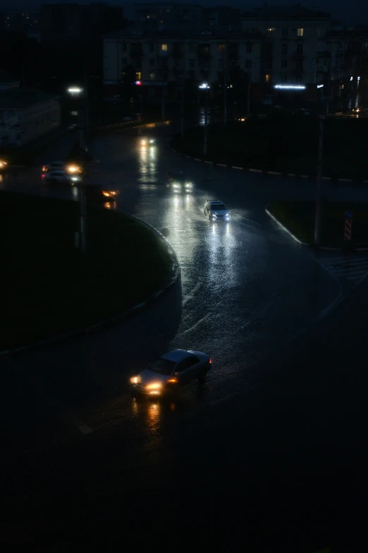 some cars are driving at night in the rain