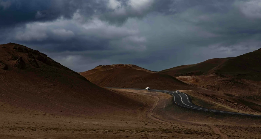 a long white truck is on a wide, winding road