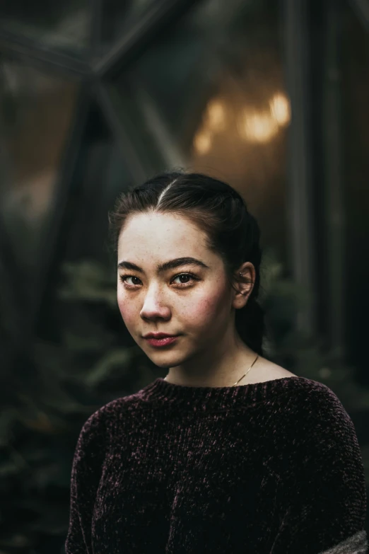 a woman with a messy ponytail standing near plants