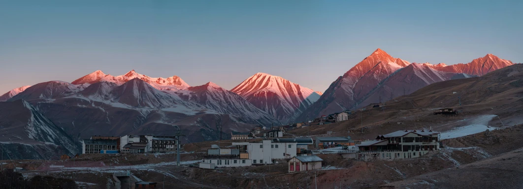 the mountains in the background and houses on a snowy hill