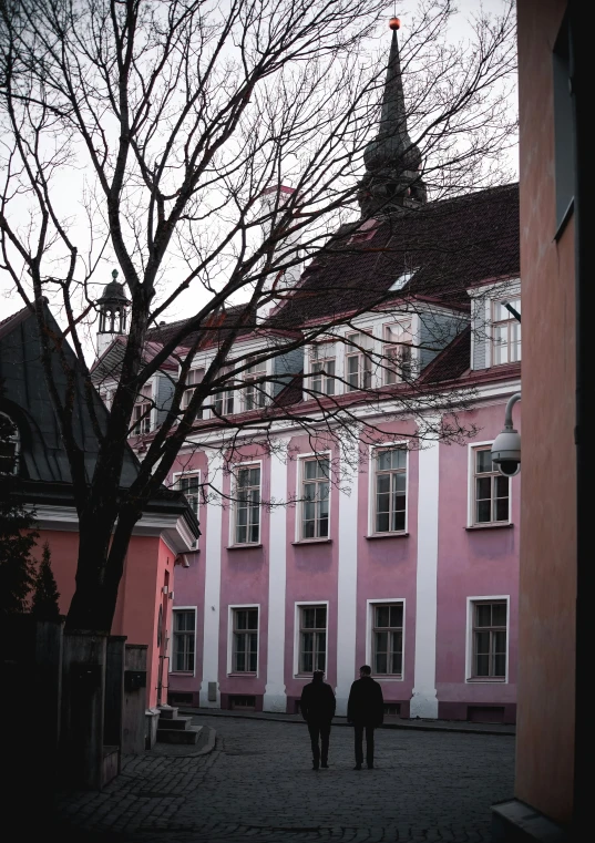 two people walking by a building and tree