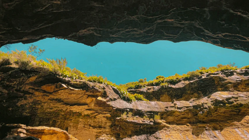 an open window in the side of a cave overlooking a lake