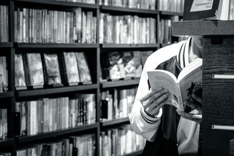 a person reading a book in front of a bunch of books