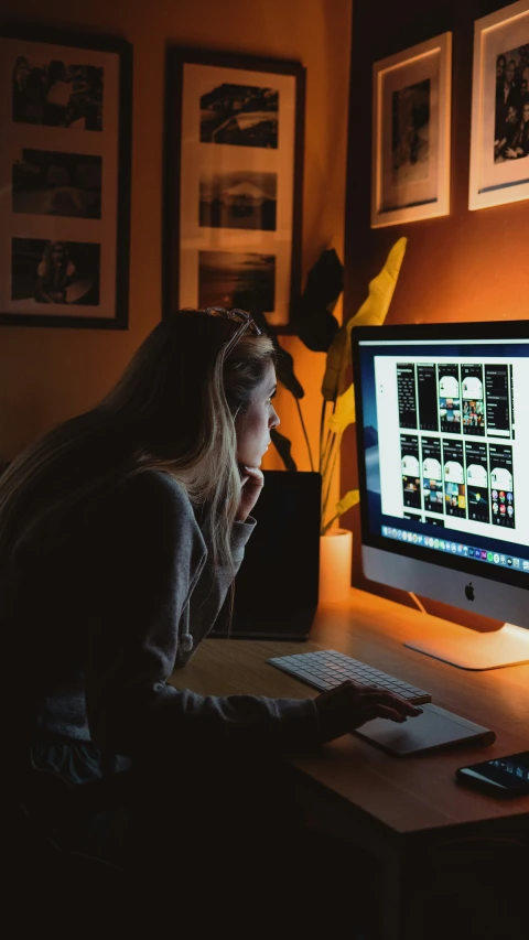 a woman sits in front of a computer at night