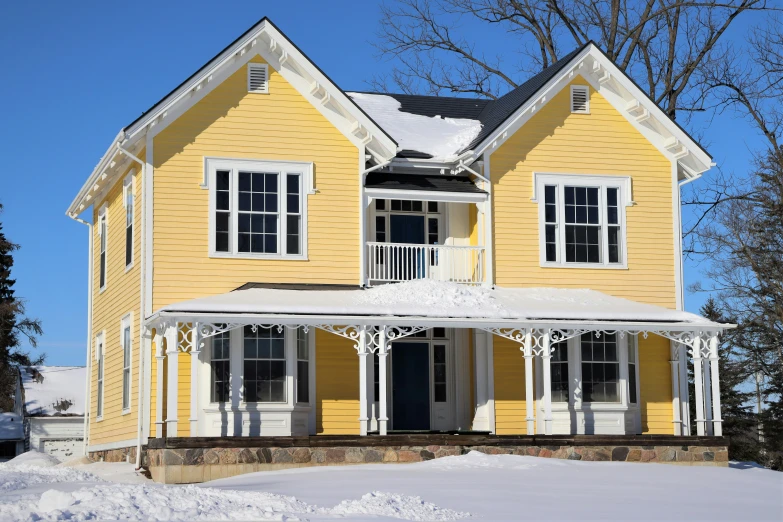 a yellow house that is on a snow covered hill