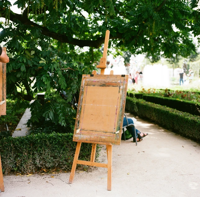 someone is painting on an easel in a garden