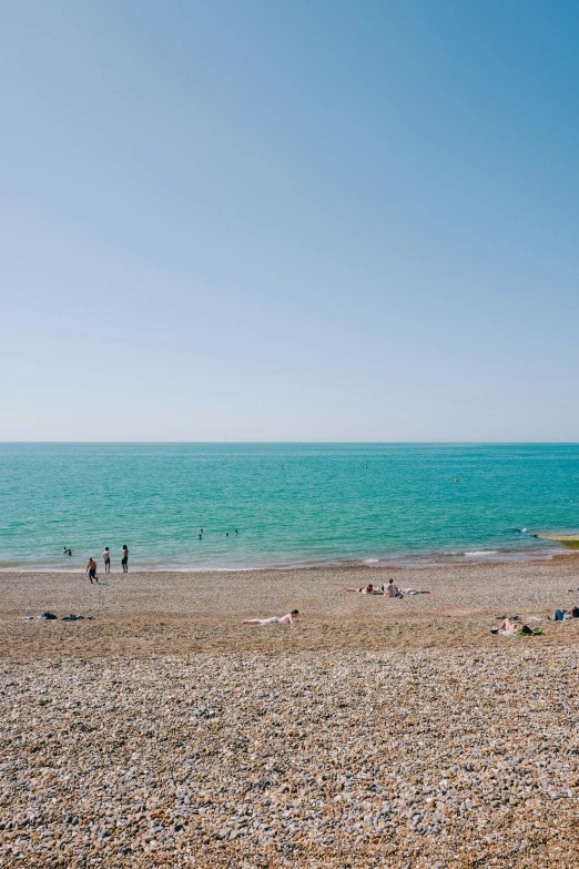 people stand on the beach with an umbrella near the ocean