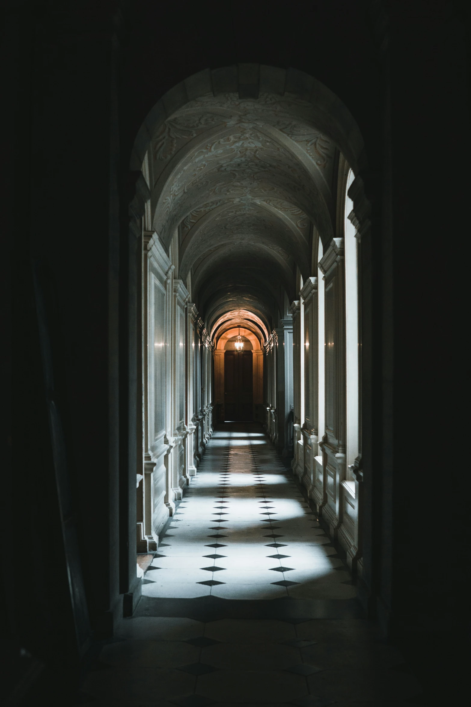 an empty dark hallway has several small pillars