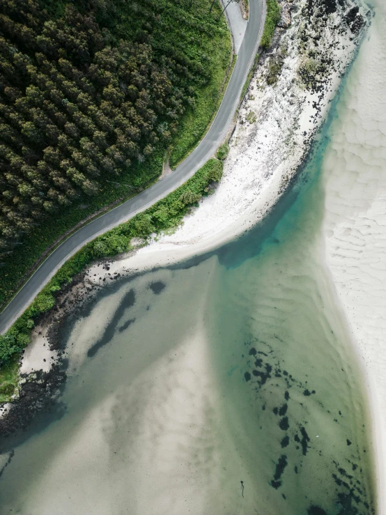 an aerial view of a beach and a road on the sand