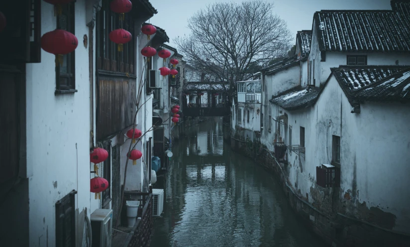 a narrow stream flowing between white buildings with red lanterns