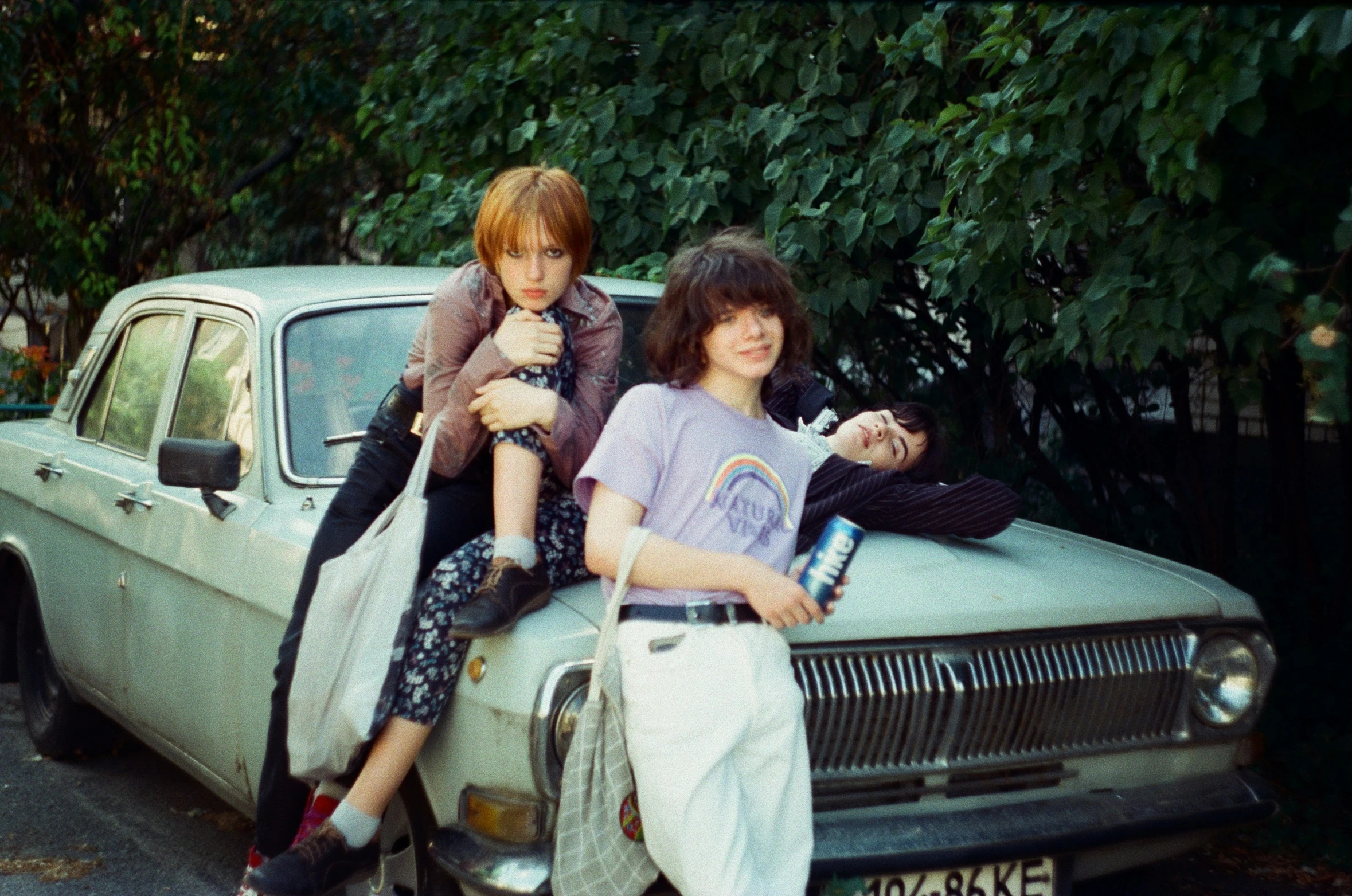 two people sitting on the hood of an old car