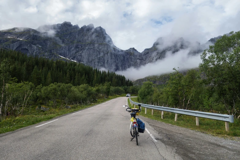 a man riding on the back of a bicycle down a road