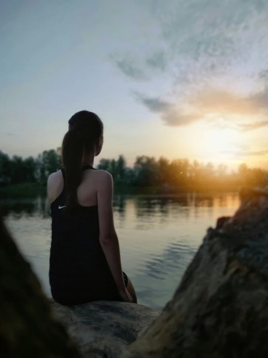 a woman is standing on a rock near the water