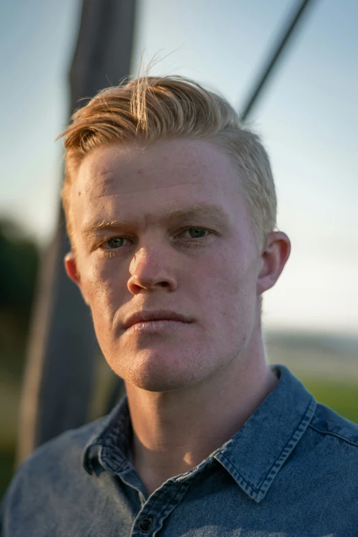 a young blonde man with very thick hair staring at the camera