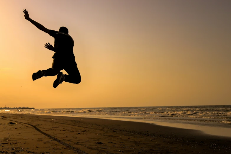 a man jumping up and down into the air on a beach