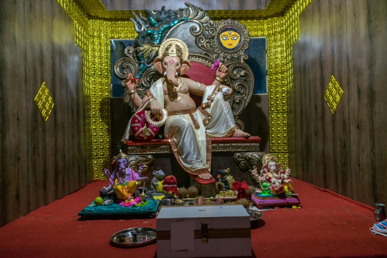 an ornate statue of ganesh sits on a chair