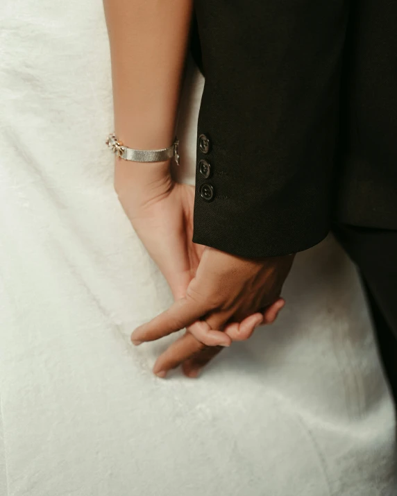 the couple hold hands while the wedding dress hangs down