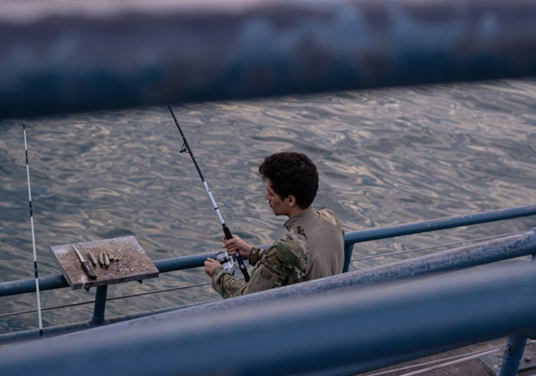a guy sitting on the edge of a boat fishing