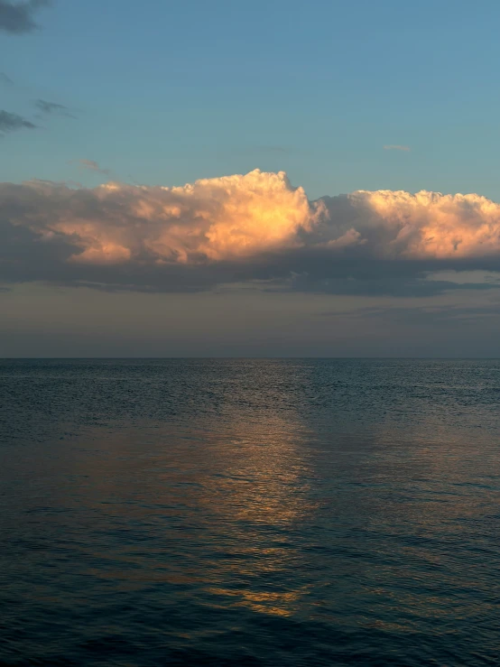 a sail boat floats in the ocean under an ominous sky