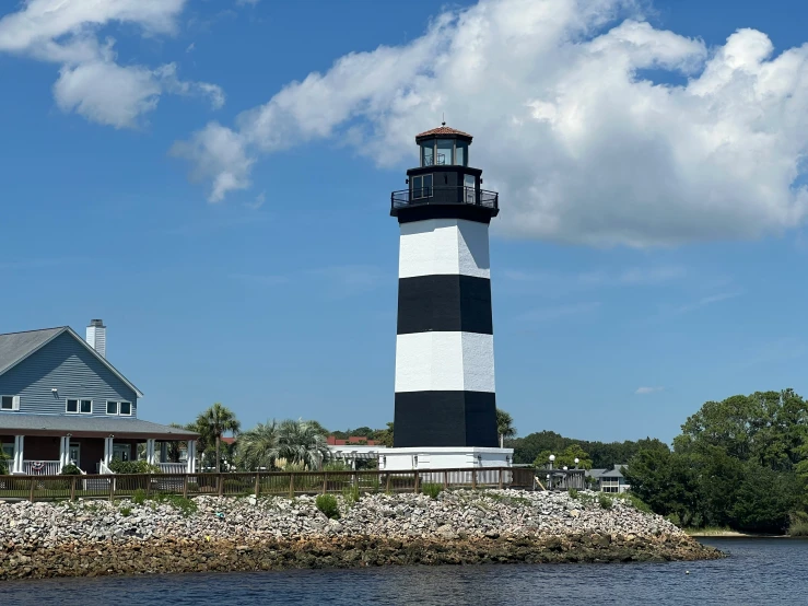 a light house sits along the water next to a large lighthouse