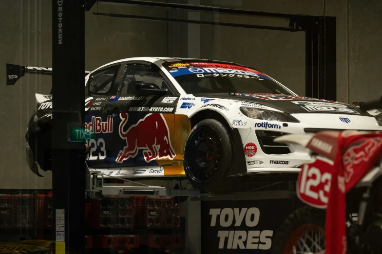 a rally car sits in a garage at the wheel