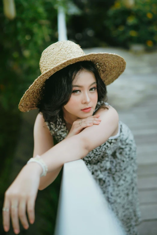 a beautiful woman with a hat standing by a wall