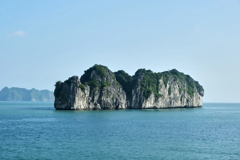 an island is in the ocean with several small rocks and trees