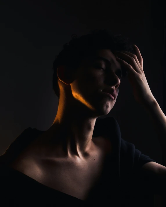 a man in dark room holding his head