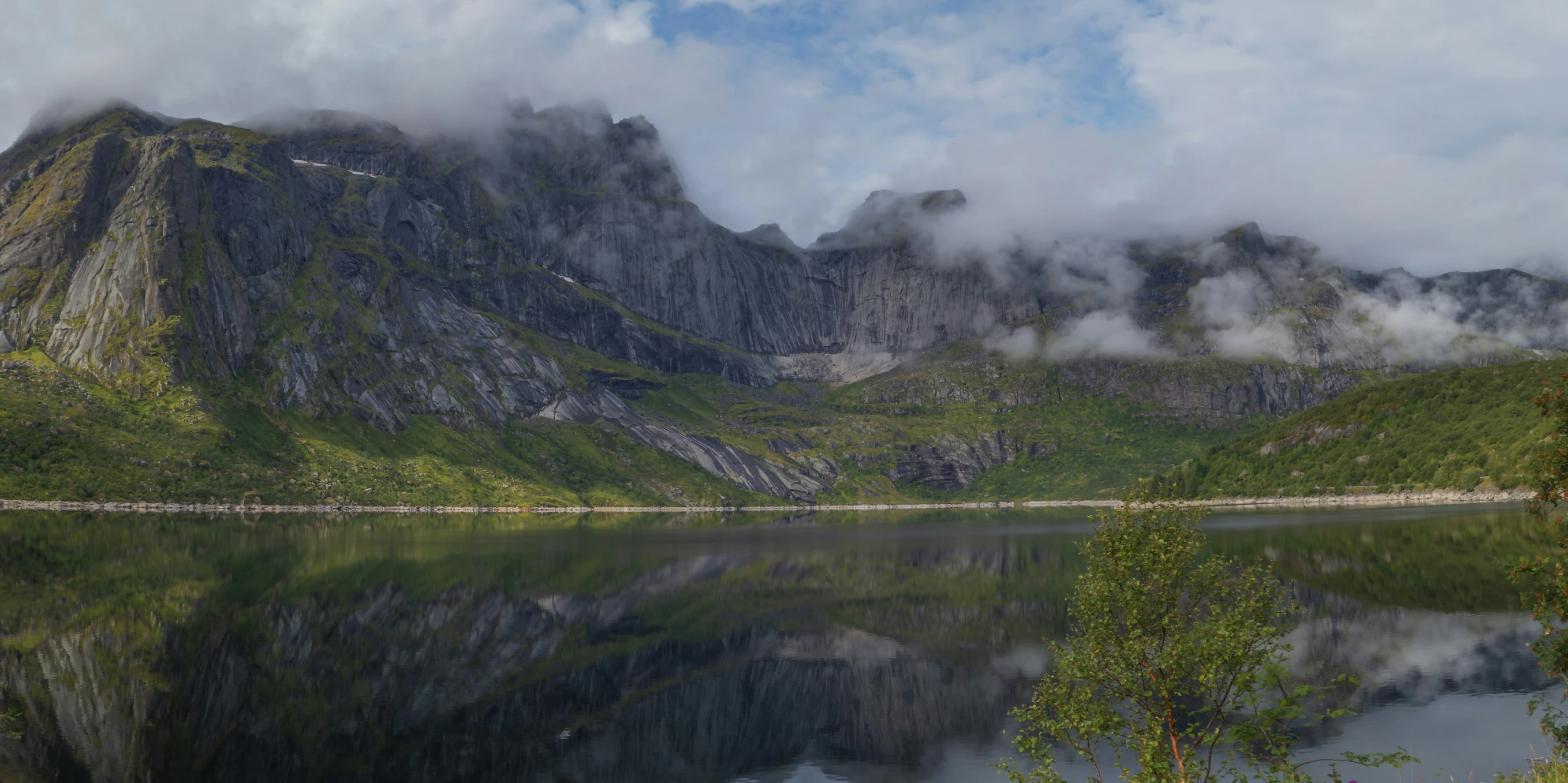 a lake with mountains in the background and mist on the ground