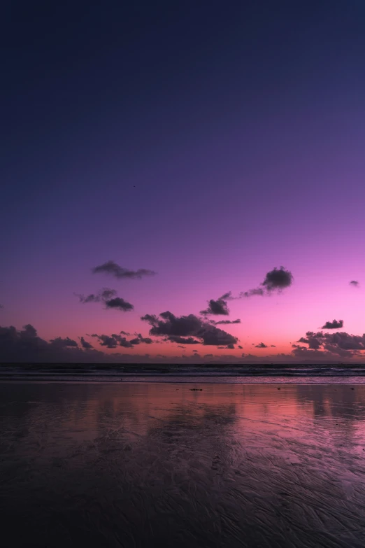 an ocean view at sunset with clouds reflected in the sand