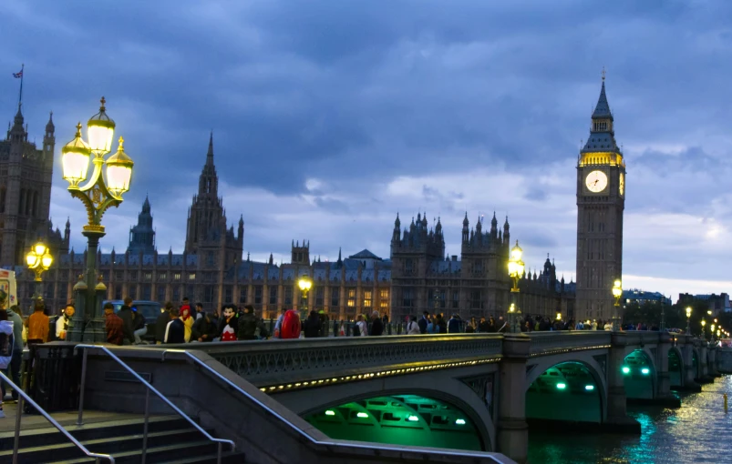 big ben with lights and tourists walking over bridge