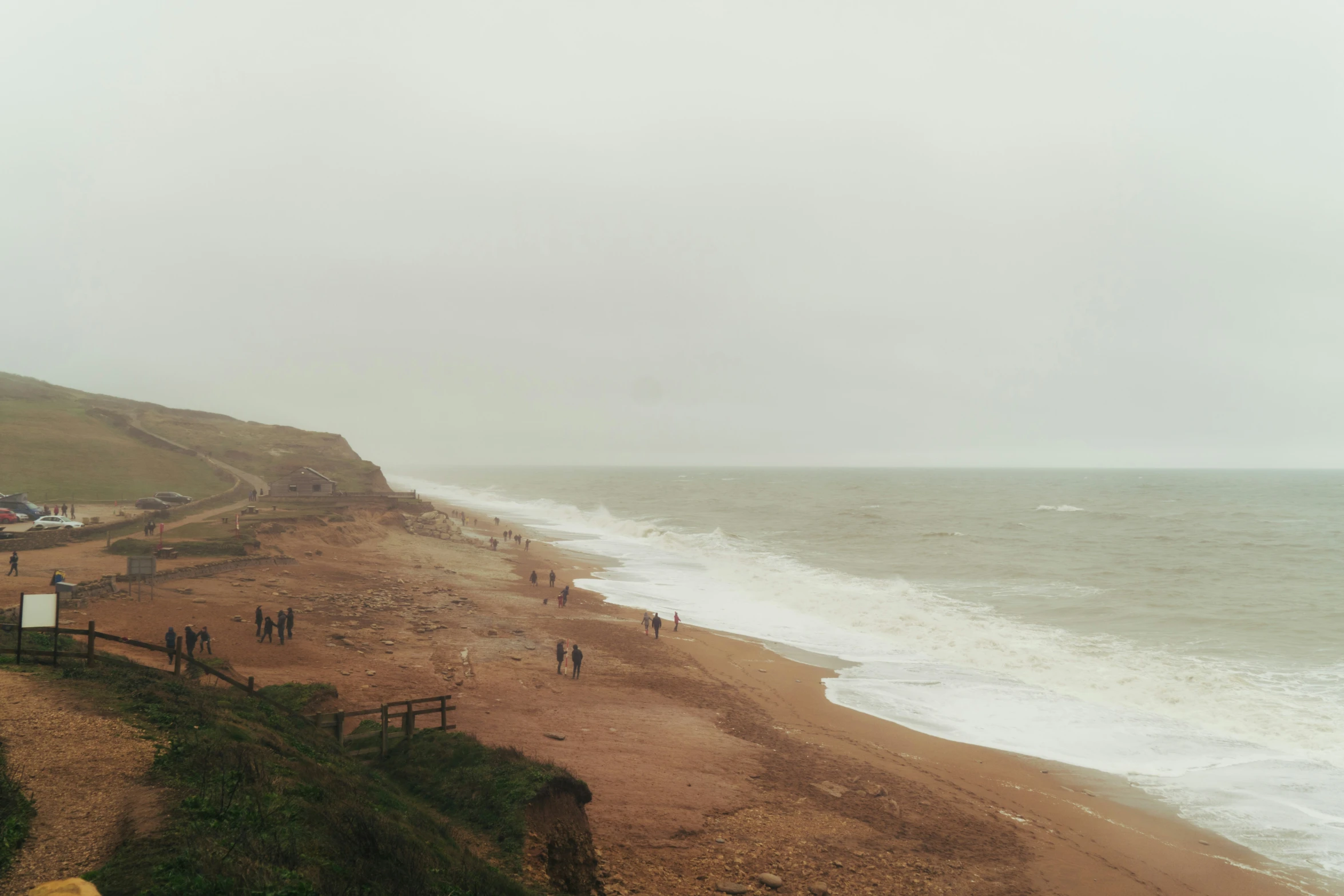 a beach side with a bunch of people walking on it