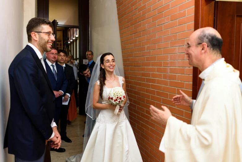 a bride and groom are smiling at each other as they stand in front of a crowd