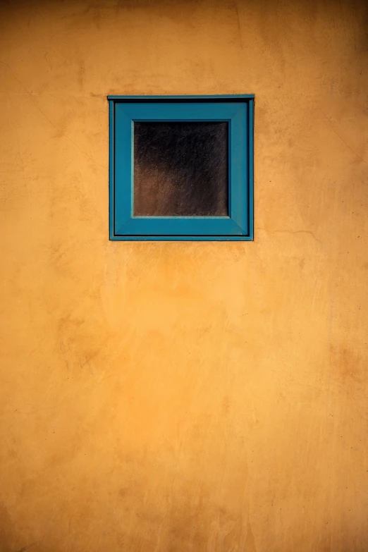 a blue window in a wall with yellow paint