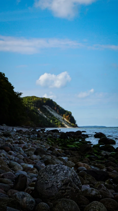 there is a sandy beach with rocks at the edge