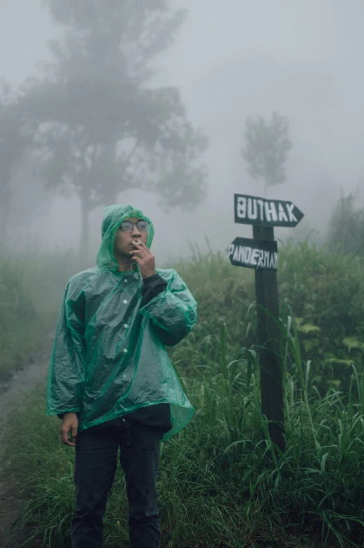 a person in green jacket next to a street sign