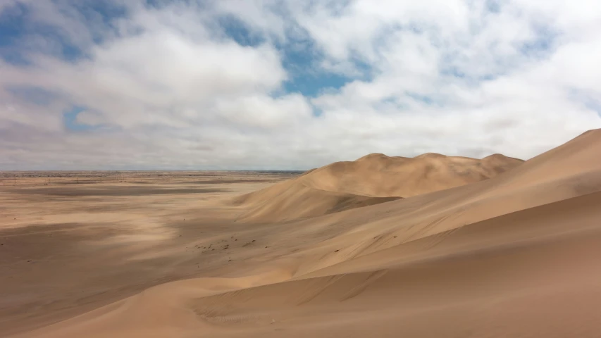 several mountains, one with no grass in the middle, and others have sand dunes at the bottom