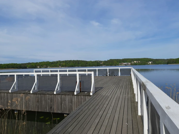 a pier with empty seats next to a body of water