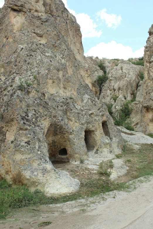 large cave like structures in the side of a rocky hill