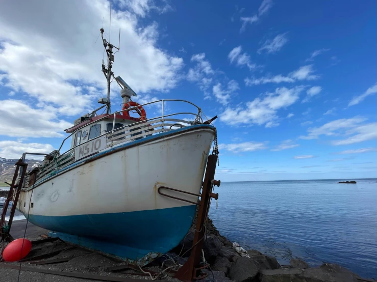 a large boat sitting on top of a pile of rocks near the ocean